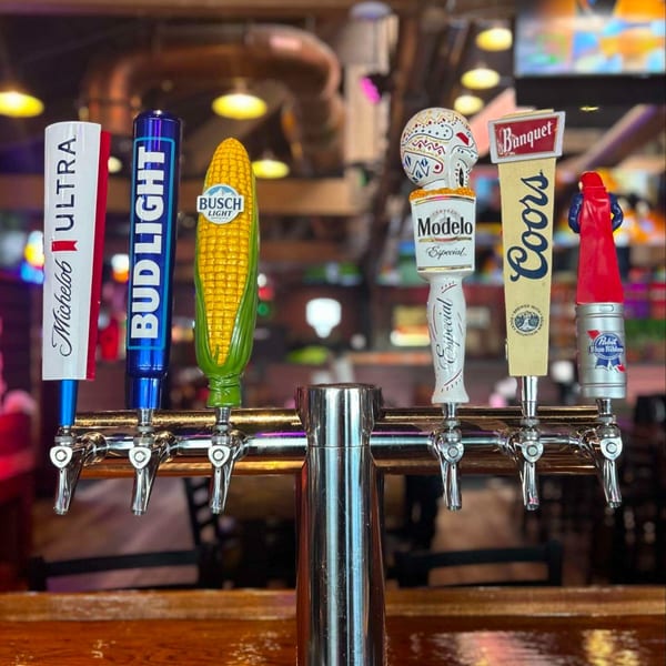 Six beer taps with various brand handles, including Michelob Ultra, Bud Light, and Modelo, at FIVE BUCKS DRINKERY.